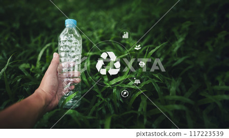 Recycle the concept of plastic water bottles,Hand holding a plastic water bottle on the grass, and an environmental icon Recycle the concept of plastic water bottles,Hand holding a plastic water bottle on the grass, and an environmental icon 117223539