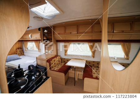 Cozy Caravan Interior with Kitchen and Sleeping Area. Ideal for Glamping, Camping, and Mobile Living Cozy Caravan Interior with Kitchen and Sleeping Area. Ideal for Glamping, Camping, and Mobile Living 117223804