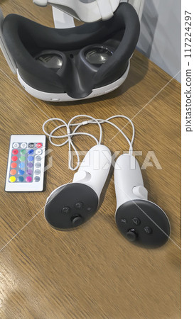 Virtual game set. VR headset. Glasses are on the table next to the control panel Virtual game set. VR headset. Glasses are on the table next to the control panel 117224297