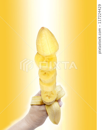 banana peeled was turned to pieces in his hand on a white-yellow background. banana peeled was turned to pieces in his hand on a white-yellow background. 117224429