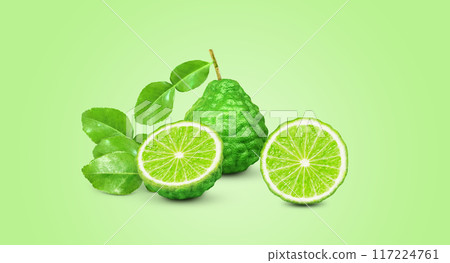 whole bergamot lime leaves and halved with bergamot lime leaves isolated on green background 117224761