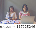 Two young female freelancer using laptop and tablet while working 117225246
