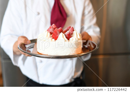 Hand holding a whole cake with short cream and strawberries Hand holding a whole cake with short cream and strawberries 117226442