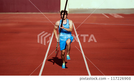 Aerial view of young man, pole vaulter practicing with precision, training at outdoor stadium, running with pole 117226908