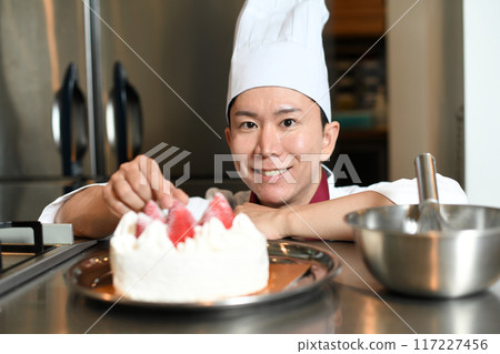 A male pastry chef making a whole cake 117227456