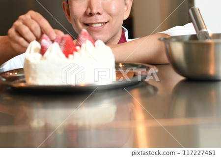 A male pastry chef making a whole cake 117227461