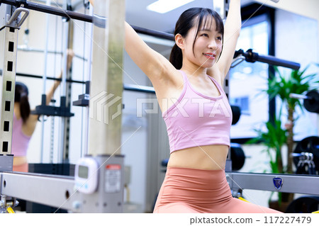 Woman working out at the gym, lat pulldown, female muscle training, workout Woman working out at the gym, lat pulldown, female muscle training, workout 117227479