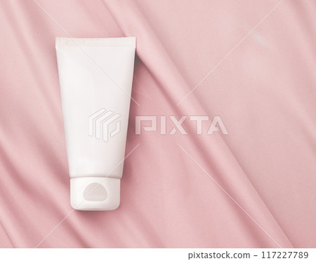 White Cosmetic Tube Positioned Gracefully on a Pink Fabric Background 117227789