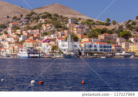 Bright colorful houses on the shore of the bay in the Greek fishing village Symi 117227869