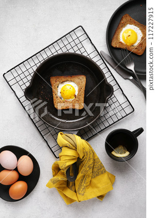 Fried eggs with toast in a frying pan on a light background with tea . breakfast idea. Top view, copy space. 117227915