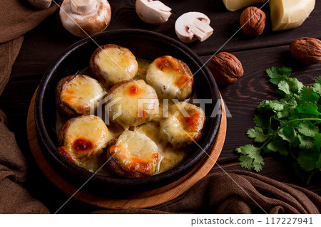Traditional Georgian dish, appetizer, stuffed mushrooms, Sulguni cheese, baked in a Ketzi clay pan, on a wooden table, close-up, no people, 117227941