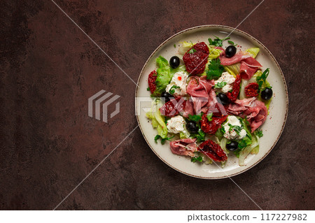 salad with dried tomatoes, prosciutto, soft cheese, olives, homemade, top view, 117227982