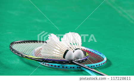 White badminton shuttlecocks and badminton rackets on green floor indoor badminton court White badminton shuttlecocks and badminton rackets on green floor indoor badminton court 117228611