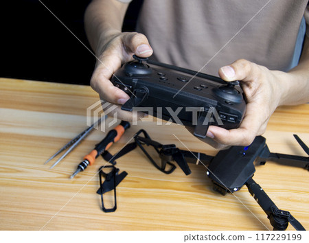 Professional mechanic repairing a drone, setting it up, on a table with various tools. in modern workshop Professional mechanic repairing a drone, setting it up, on a table with various tools. in modern workshop 117229199