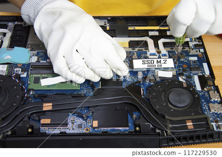 Top view of mechanic repairing computer, installing M.2 SSD 117229530