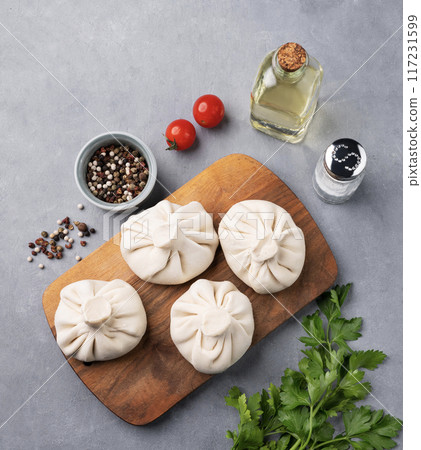 Georgian Khinkali dumplings with meat, herbs and spices on a wooden board not cooked 117231599