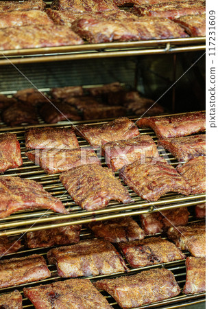 Grilled barbecue pork ribs in a smoker at the factory. The concept of a delicious snack for a picnic Grilled barbecue pork ribs in a smoker at the factory. The concept of a delicious snack for a picnic 117231609