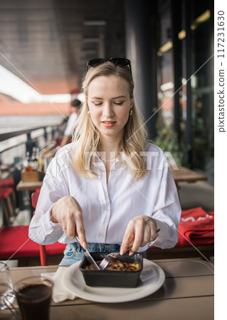 Blonde gen z woman eating lasagna in the cafe on break. Gen z girl spend time in restaurant Blonde gen z woman eating lasagna in the cafe on break. Gen z girl spend time in restaurant 117231630