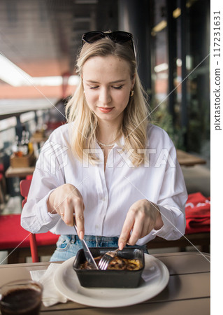 Blonde gen z woman eating lasagna in the cafe on break. Gen z girl spend time in restaurant Blonde gen z woman eating lasagna in the cafe on break. Gen z girl spend time in restaurant 117231631