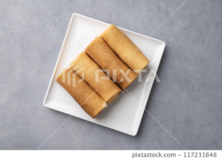 Homemade roll crepes on a white plate on a blue background. Healthy food concept. Homemade roll crepes on a white plate on a blue background. Healthy food concept. 117231648