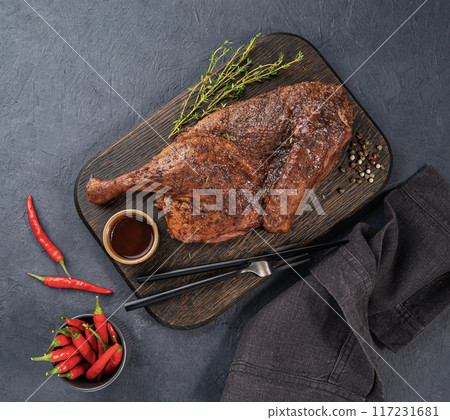 BBQ roast duck or chicken in spices and marinade on a wooden board with fresh spices BBQ roast duck or chicken in spices and marinade on a wooden board with fresh spices 117231681