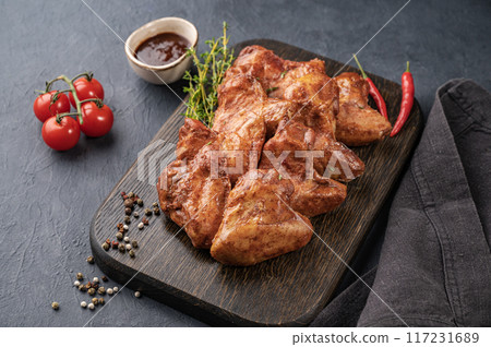 Grilled spicy chicken wings bbq  with sauce, tomato and fresh herb on a wooden board  117231689
