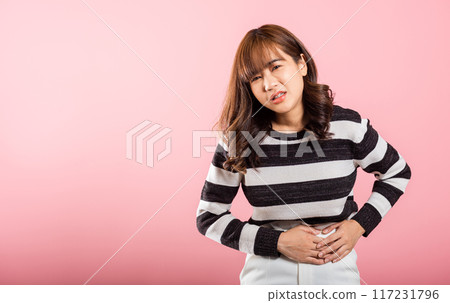 Portrait of Asian beautiful young woman has stomachache, female abdominal pain suffering from stomach ache, studio shot isolated on pink background, period pain, Health and medical gastritis concept Portrait of Asian beautiful young woman has stomachache, female abdominal pain suffering from stomach ache, studio shot isolated on pink background, period pain, Health and medical gastritis concept 117231796