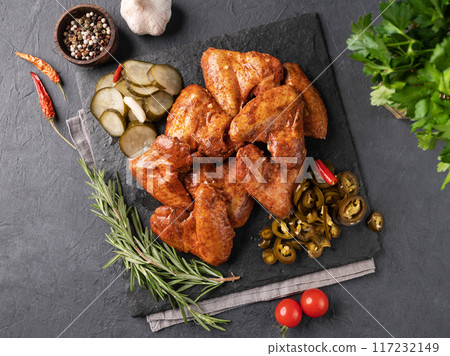 Roasted chicken wings bbq with pickled cucumber and jalapeno and fresh herb on a black slate  117232149
