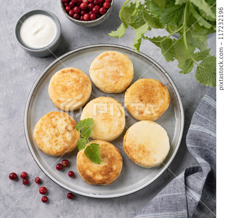 Flat lay pancakes with cottage cheese with fresh blerries and sour cream on a gray background  Flat lay pancakes with cottage cheese with fresh blerries and sour cream on a gray background  117232196