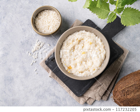 Rice porridge with fruit and coconut milk in bowl on a blue background. Concept healthy breakfast. Rice porridge with fruit and coconut milk in bowl on a blue background. Concept healthy breakfast. 117232205