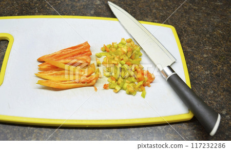 sweet bell pepper on a board, next to a kitchen knife 117232286