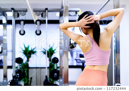 A young woman posing from behind in a sports gym, diet, personal gym, muscle training, beautiful buttocks training 117232444