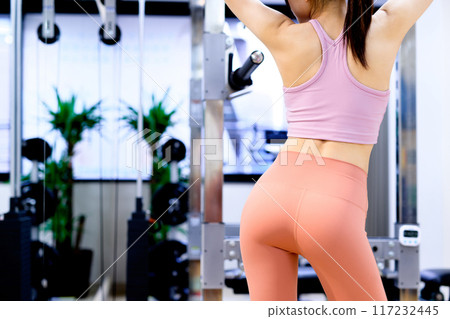A young woman posing from behind in a sports gym, diet, personal gym, muscle training, beautiful buttocks training 117232445