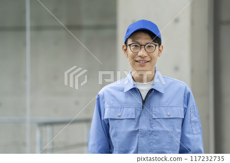 一名三十多歲的男子穿著工作服對著鏡頭微笑 一名三十多歲的男子穿著工作服對著鏡頭微笑 117232735