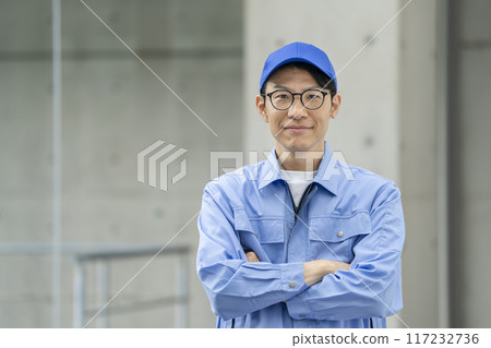 一名30多歲的男子穿著工作服,雙手交叉看著鏡頭 一名30多歲的男子穿著工作服,雙手交叉看著鏡頭 117232736