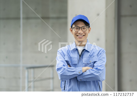 A man in his 30s wearing work clothes with his arms crossed, looking at the camera A man in his 30s wearing work clothes with his arms crossed, looking at the camera 117232737