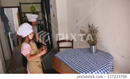A mother and daughter spend quality time baking croissants together in a cozy kitchen. The little girl thoughtfully arranges baked goods while learning the art of cooking. A mother and daughter spend quality time baking croissants together in a cozy kitchen. The little girl thoughtfully arranges baked goods while learning the art of cooking. 117233706