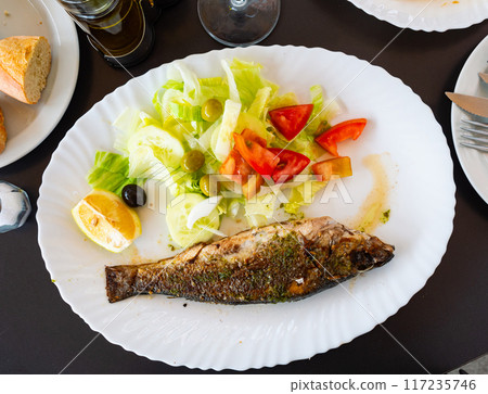 Grilled seabass with colorful fresh salad and lemon wedge 117235746