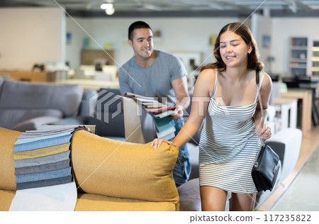 Boyfriend and girlfriend are choosing color of sofa in furniture store 117235822