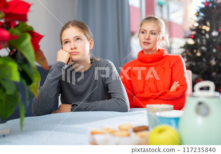 Schoolgirl sitting at the table after quarrel with mother Schoolgirl sitting at the table after quarrel with mother 117235840