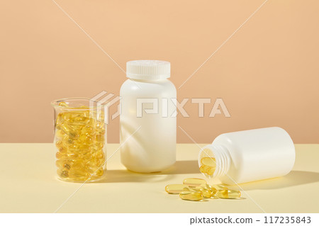 Mockup for fish oil advertisement with two white blank label bottles and glass beaker contains yellow supplement capsules, omega-3 in fish oil help protect eye health and reduce long-term inflammation 117235843