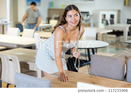 Interested girl choosing furniture for dining room in store Interested girl choosing furniture for dining room in store 117235906