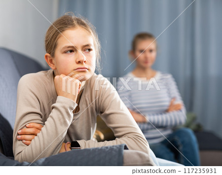 Sad female and daughter sitting at sofa and having quarrel 117235931