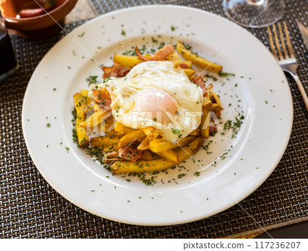 Scrambled eggs with bacon and french fries served on plate 117236207