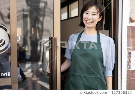 Smiling female staff member at the entrance of the cafe Smiling female staff member at the entrance of the cafe 117236353