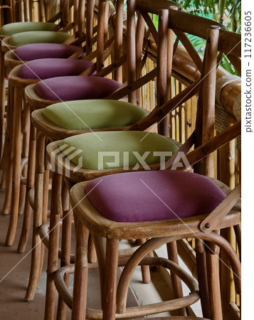 A row of chairs made of wood with cushions in purple and green colors 117236605