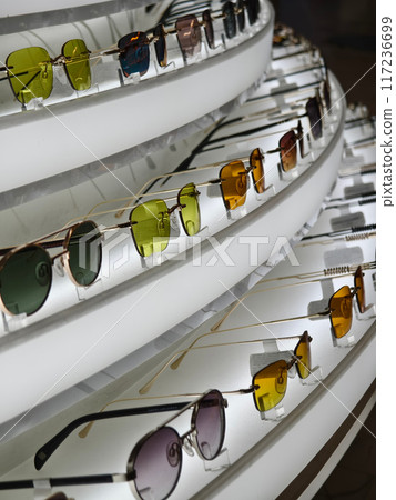 There are multiple pairs of sunglasses arranged neatly on a shelf 117236699