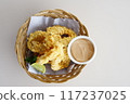 A close-up photo of a plate overflowing with golden fried calamari ring. 117237025