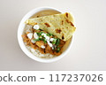 A bowl of chicken tikka masala w slice of naan bread and yogurt on a plate. 117237026