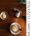 Denpasar, Bali, Saturday, 19 January 2019. Close-up photo of two cappuccino cups with sunglasses and a camera on a wooden table 117237032